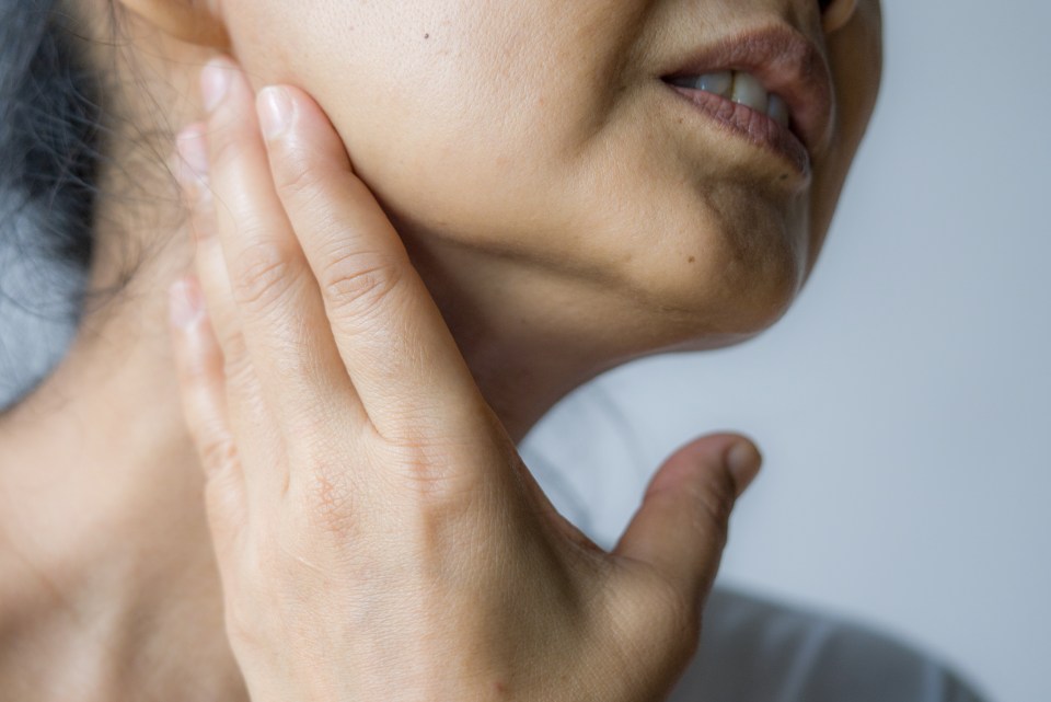 Woman holding her jaw in pain.