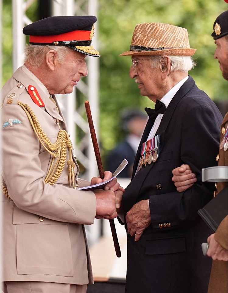 King Charles shaking hands with a veteran at a remembrance service.
