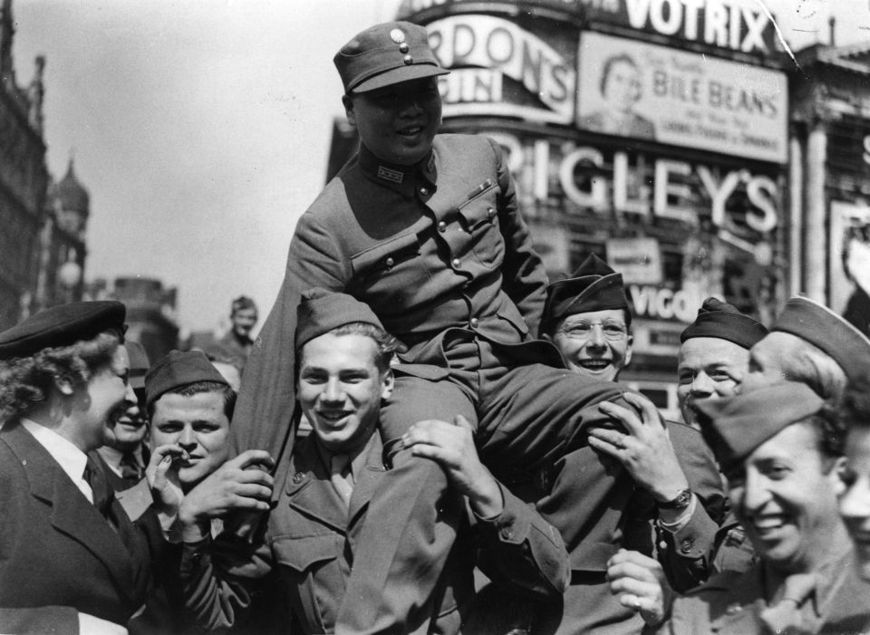 A member of the Chinese Military Mission in London is carried on the shoulders of a celebrating crowd in Piccadilly Circus.