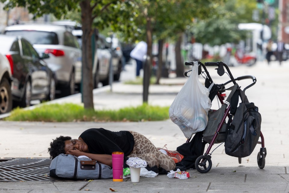 Person sleeping on a city sidewalk.