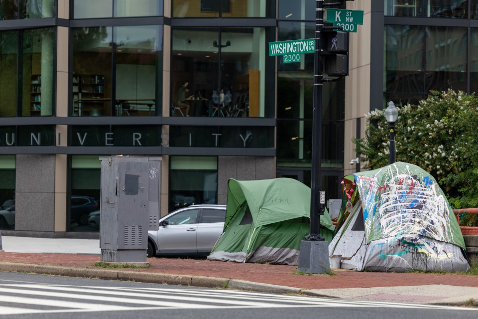 Two tents set up on a city sidewalk near a university building.
