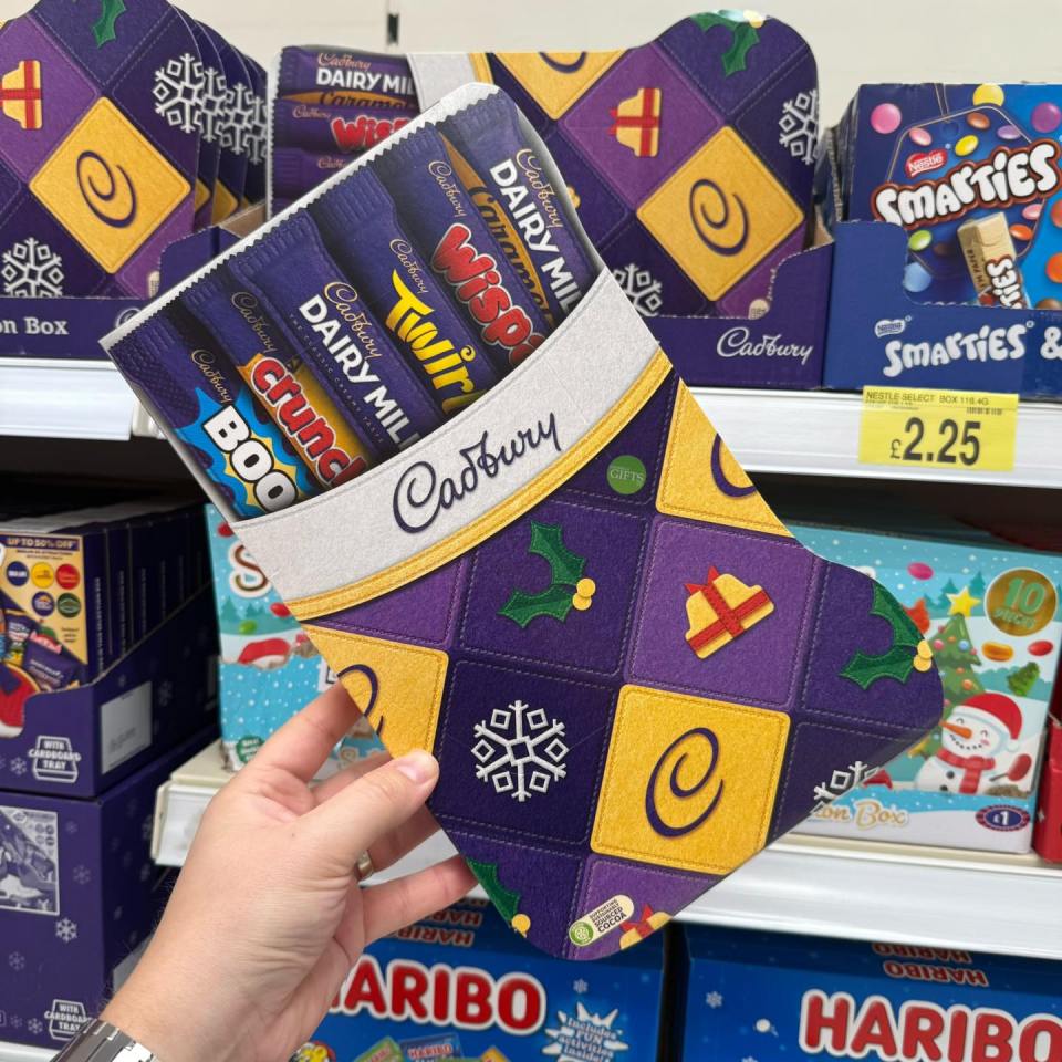Hand holding a Cadbury chocolate stocking filled with various chocolate bars.