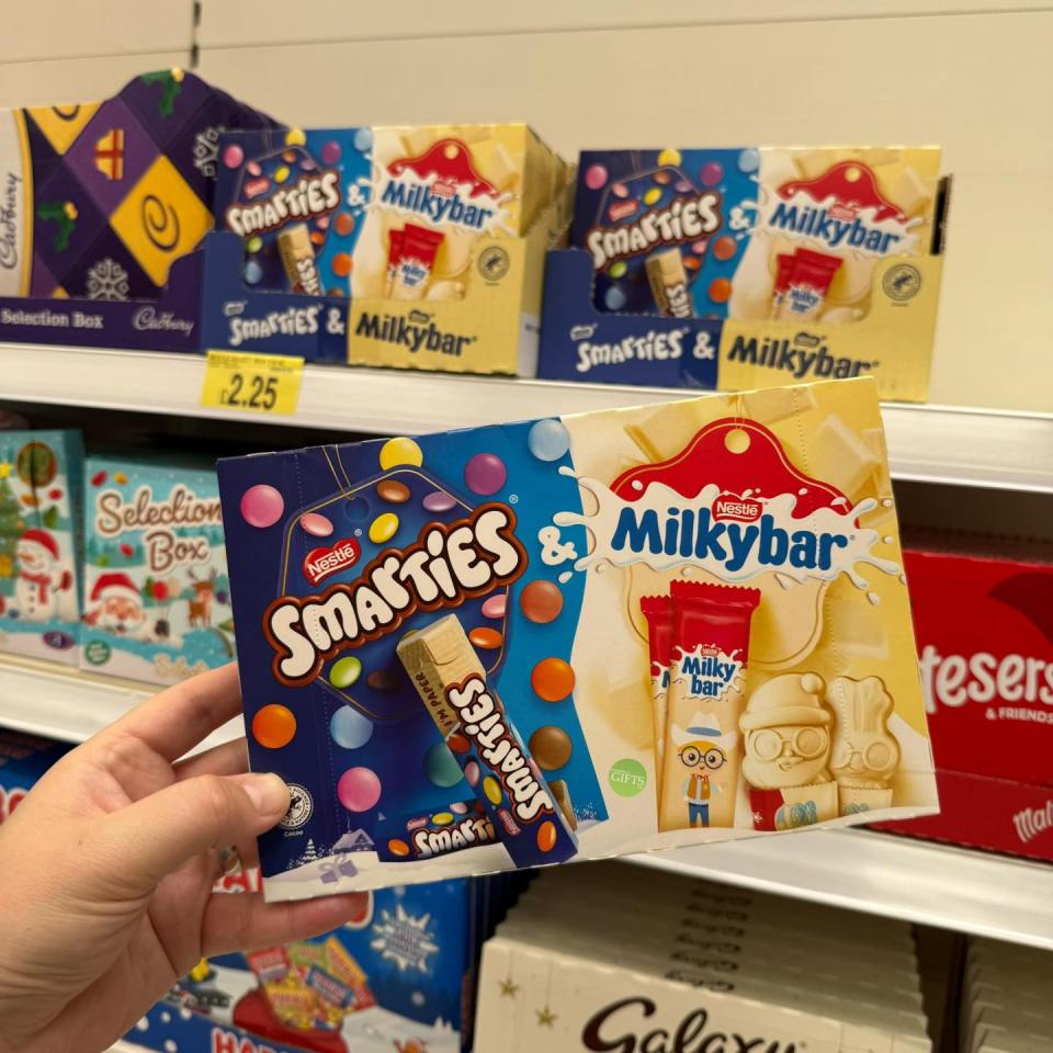 Hand holding a box of Smarties and Milkybar chocolates.