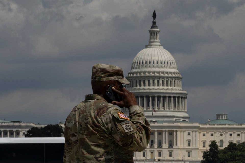 National Guardsman on phone with US Capitol in background.