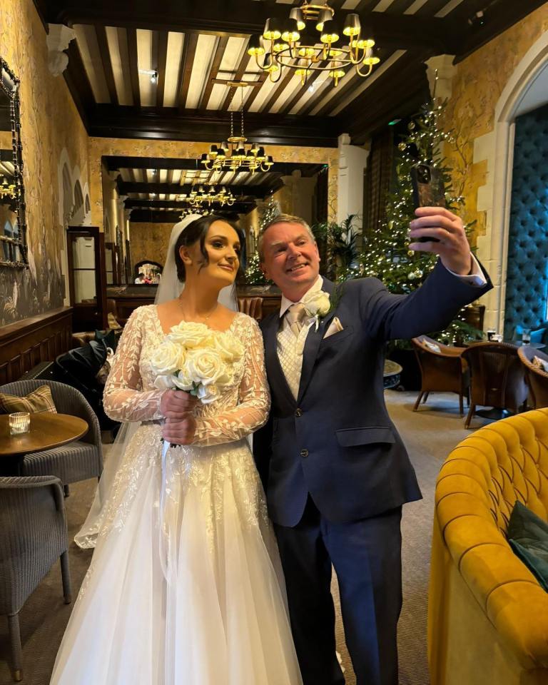 Bride and her father taking a selfie at a wedding.