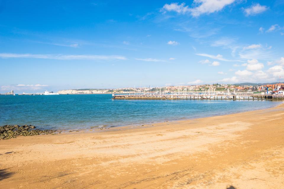 Sandy beach with a pier and marina in Getxo, Spain.