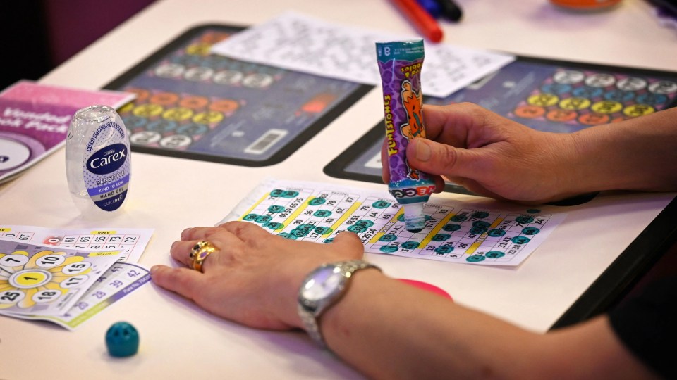 Person playing bingo and marking numbers on their card.