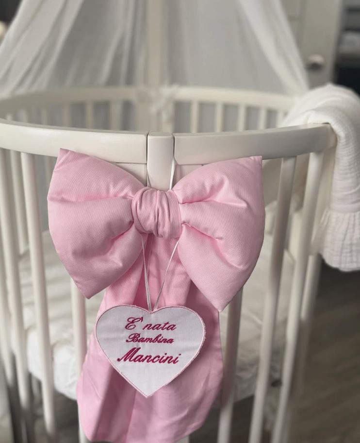 Pink bow and heart-shaped tag announcing the birth of baby Mancini.