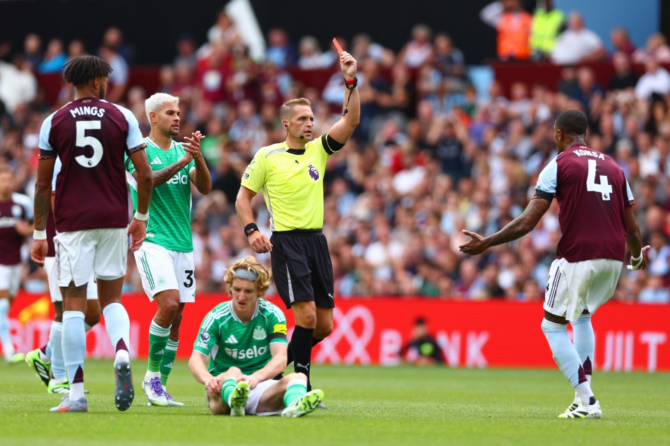 Referee showing Ezri Konsa a red card during a soccer game.