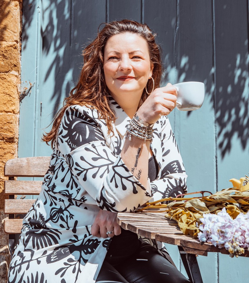 Woman sitting outdoors holding a coffee cup.
