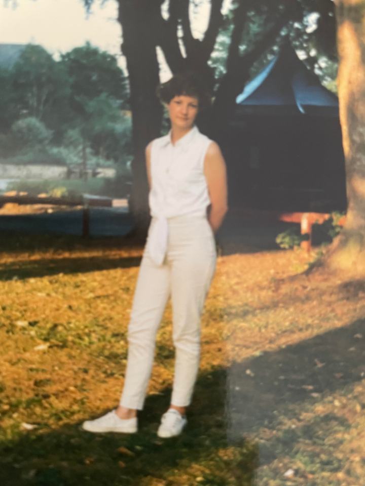 Photo of a young woman in a white outfit standing outdoors.