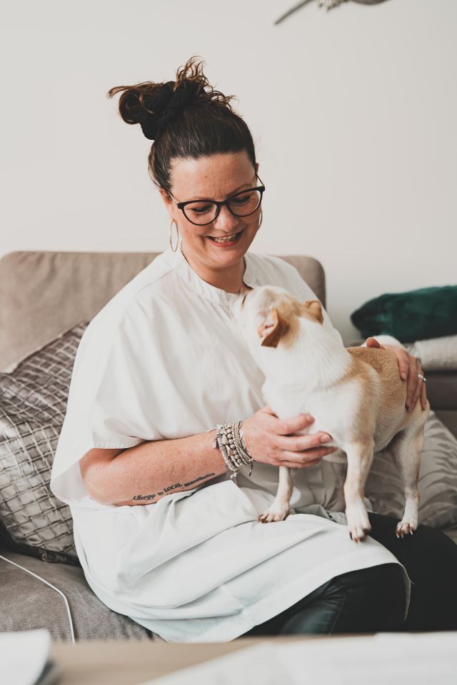 Woman sitting on a couch holding a small dog.