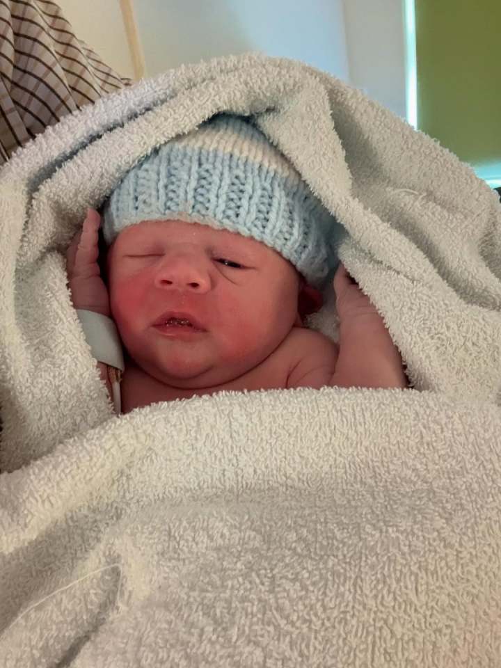 Newborn baby swaddled in a towel and wearing a knit hat.