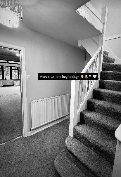 Black and white photo of a hallway with stairs and a radiator.