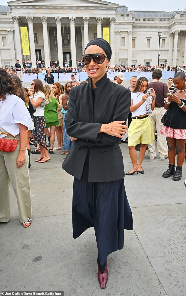 She finished her look with a long navy skirt, black tights and added inches to her statuesque frame with a person of marron heels