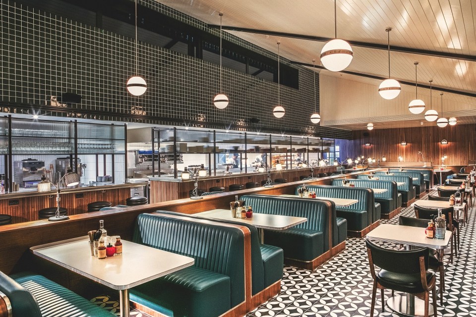 Interior view of a diner with teal booths and white tables.