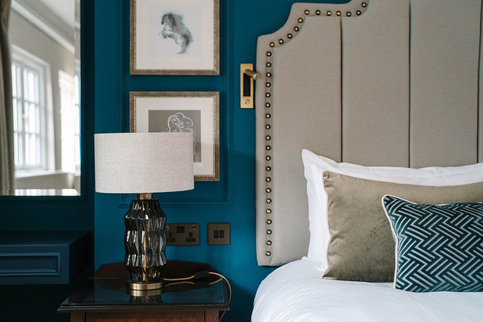 Royal Berkshire Hotel room detail: bedside table, lamp, and bed with pillows.