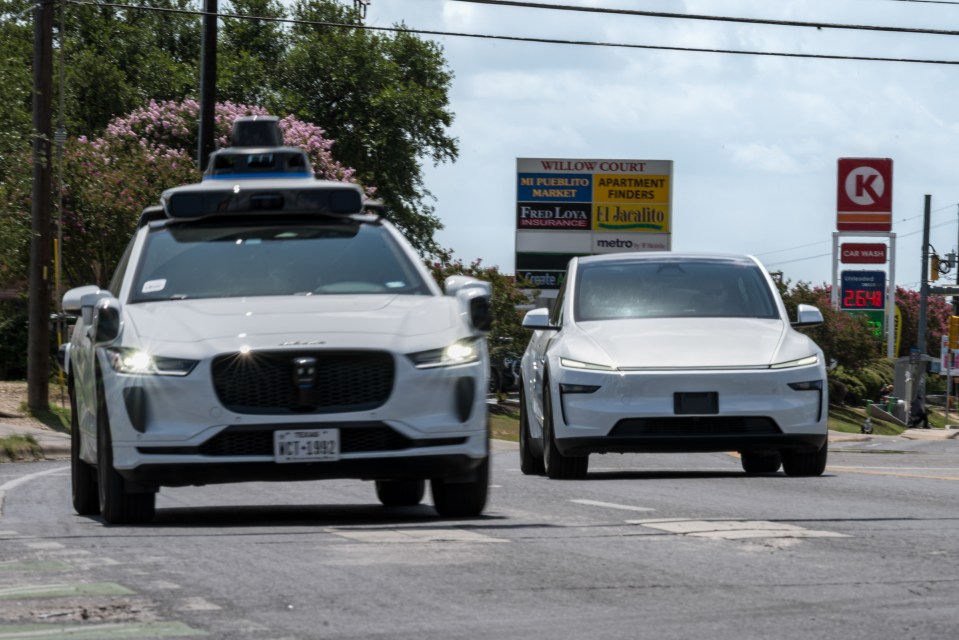 Waymo and Tesla autonomous taxis driving on a road.