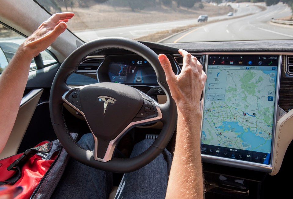 Person's hands on Tesla Model S steering wheel, Autopilot engaged.