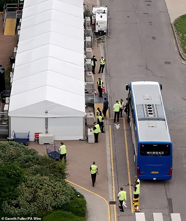 Pictured: people thought to be migrants disembark a coach at the Manston Immigration Processing Centre in Kent