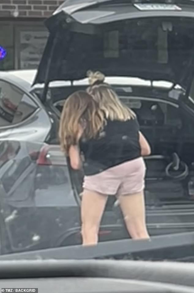 The twins were seen placing a newborn baby in a car seat into the back of a black Tesla, carefully securing the child before checking through the vehicle's trunk (pictured)