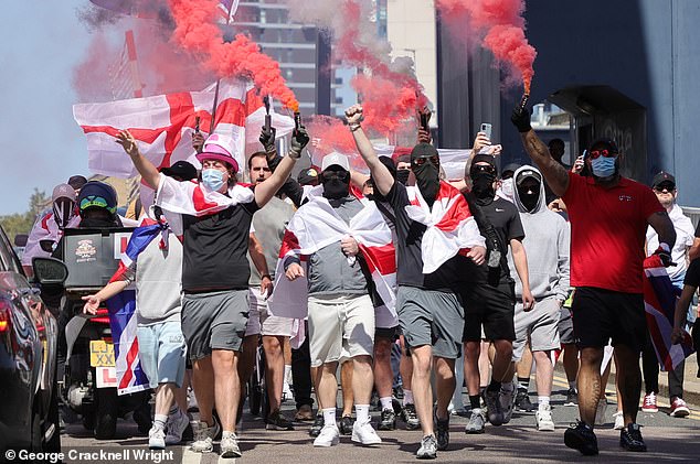 Masked protesters with flares demonstrate their opposition to the housing of asylum seekers in the Britannia International Hotel in Canary Wharf, east London, today