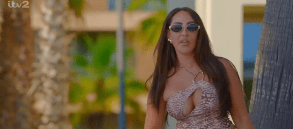 Screenshot of a woman wearing sunglasses and a patterned top.