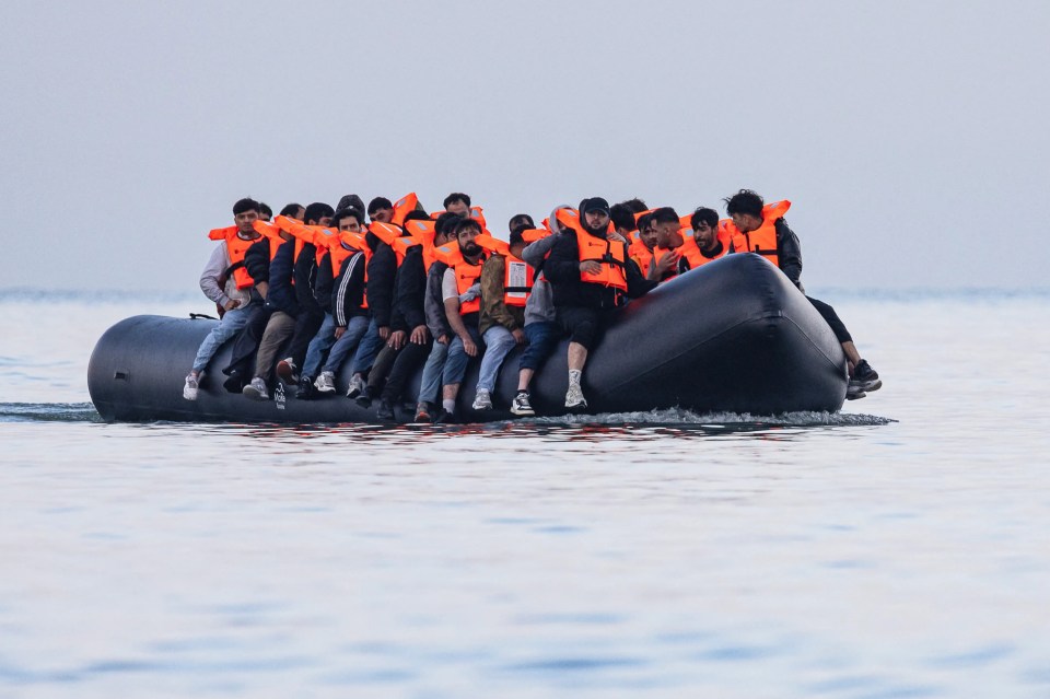 Migrants in life vests on a small boat at sea.
