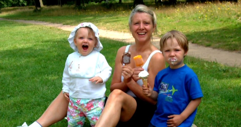 A woman and two young children eating ice cream outdoors.