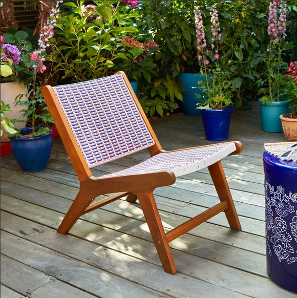 Wooden chair with patterned woven seat on a deck.