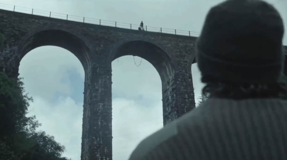 Person looking at figures on a stone bridge.