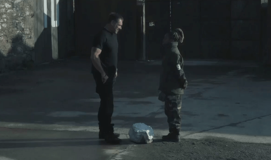 Two people facing each other with a rock between them.