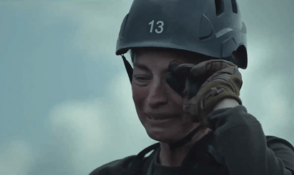 Woman in helmet wiping away tears.