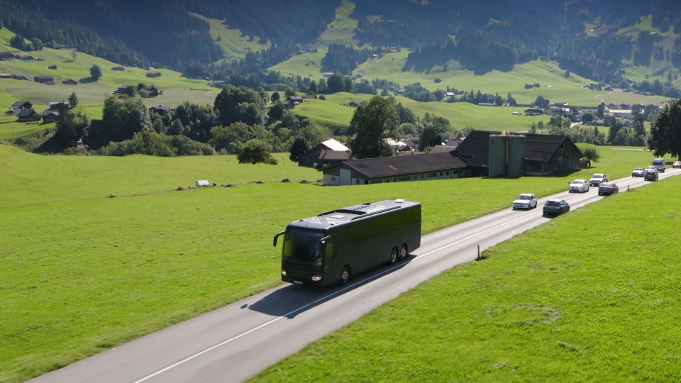 Bus driving on a road through a rural landscape.
