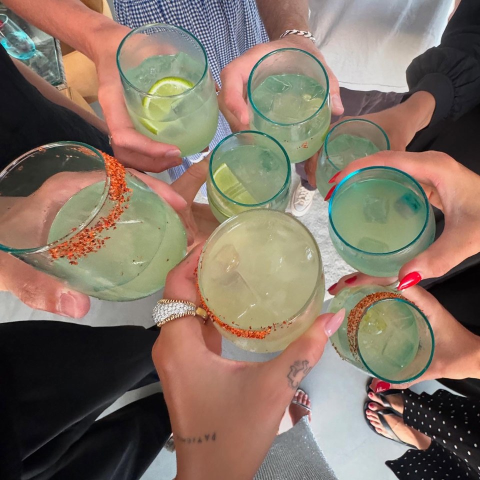 Several hands holding up glasses of margaritas.