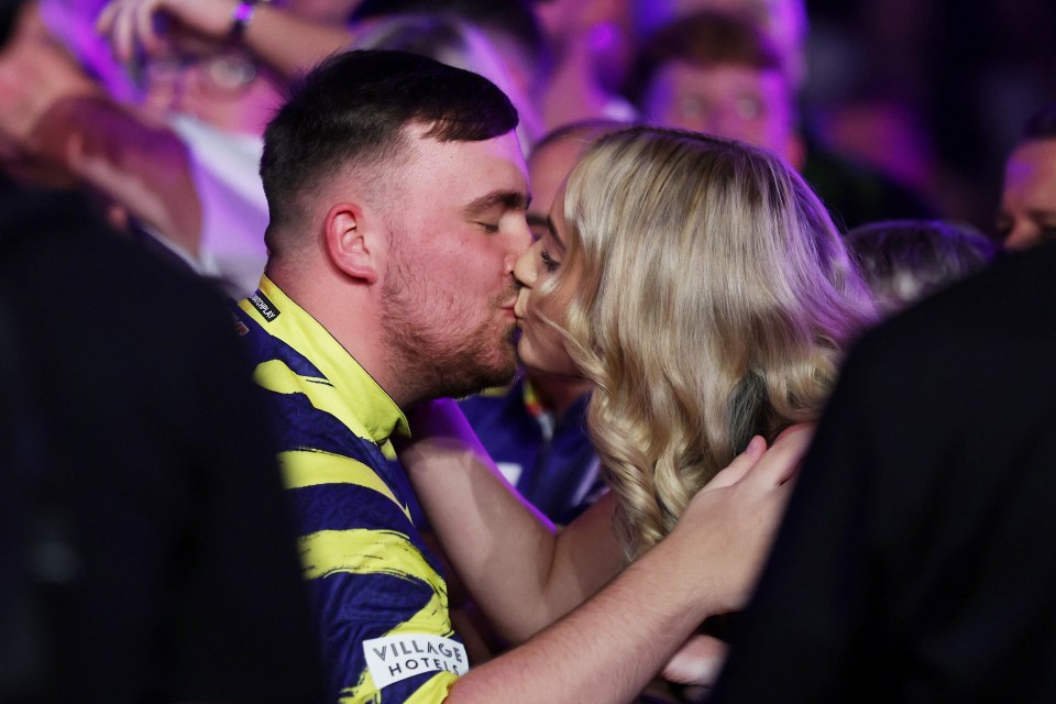 Luke Littler of England kissing Faith Millar before a darts semifinal match.