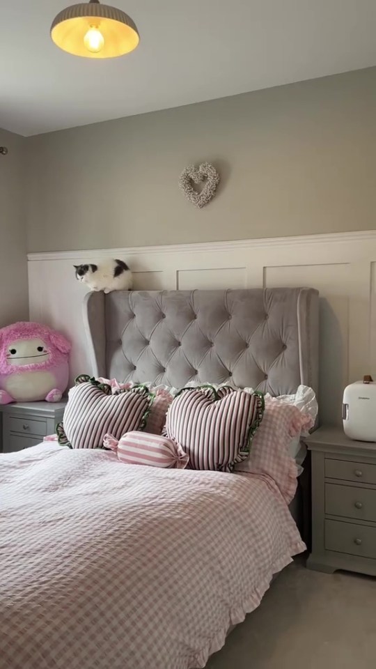 Bedroom makeover with gray headboard, pink bedding, and cat on the headboard.