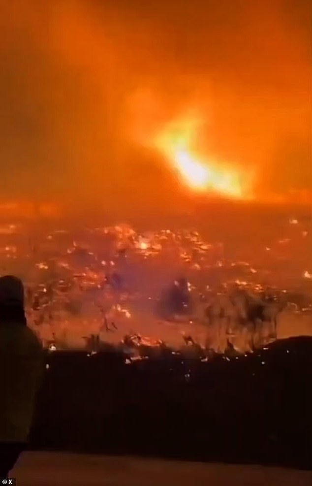 Black smoke filled the air above the burning area as the sky shines a fluorescent orange from the gargantuan flames