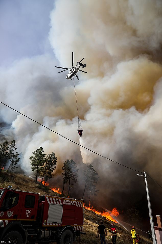 A helicopter Kamov flies over the smoke from a forest fire in Aldeia de Meas, at Pampilhosa da Serra, Portugal, 17 August 2025
