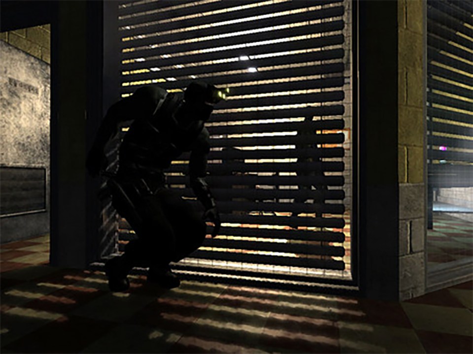 A figure in dark clothing crouching behind a roll-up door.