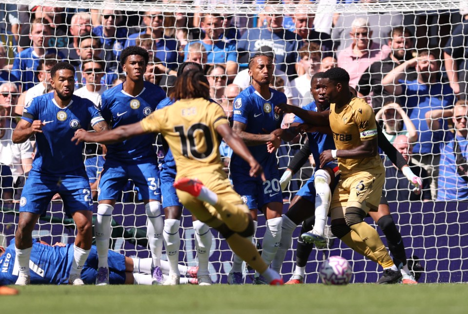 Crystal Palace player kicking a soccer ball toward the goal, Chelsea players defending.