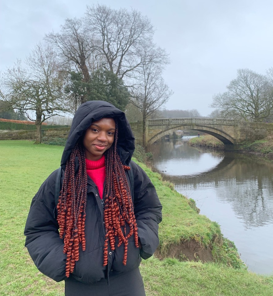 Woman standing by a river and stone bridge.
