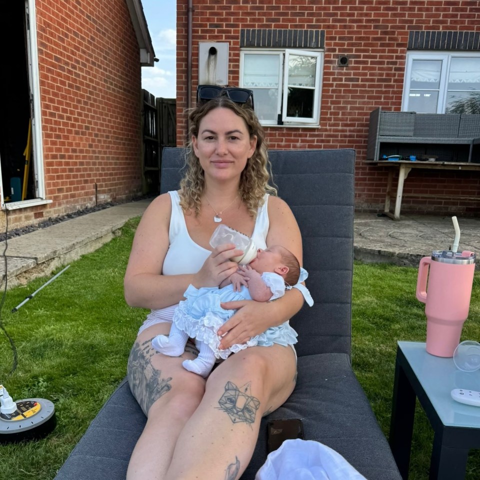 Woman bottle-feeding her newborn baby outdoors.