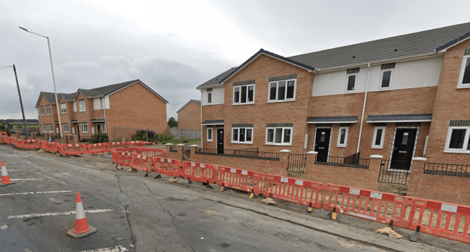 Empty houses behind a construction barrier.