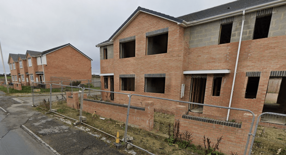 Unoccupied houses behind a construction barrier.