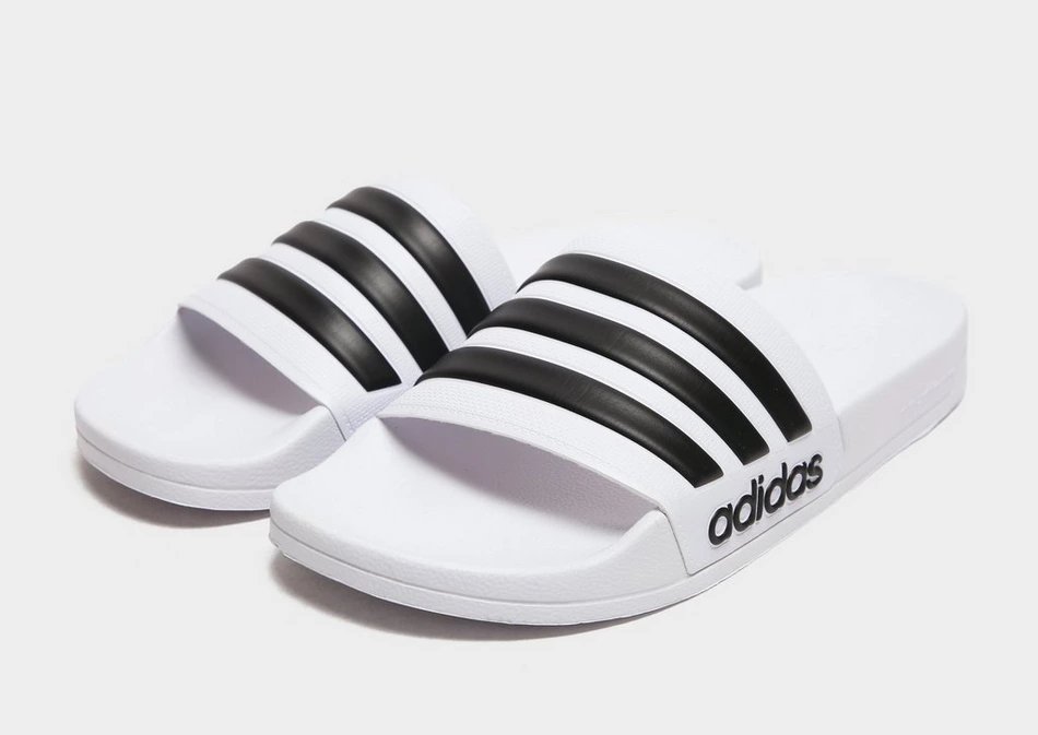 Pair of white Adidas slides with three black stripes.