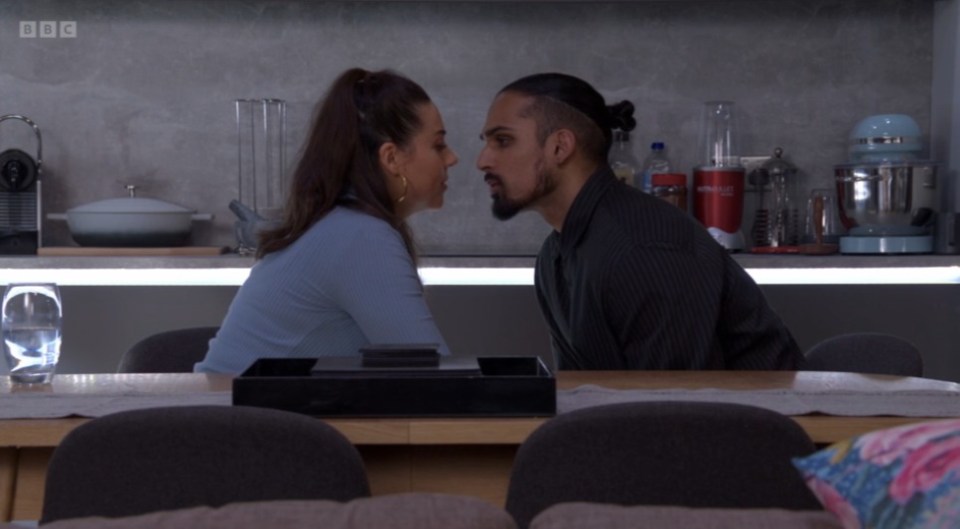 Screenshot of a man and woman facing each other in a kitchen.