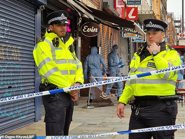 Police stand guard outside the scene of the shooting in Dalston, East London, in May last year