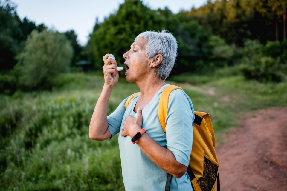 Senior woman using an asthma inhaler outdoors.