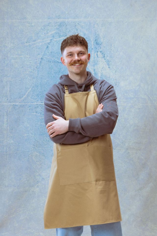 Portrait of a smiling man wearing a tan apron.